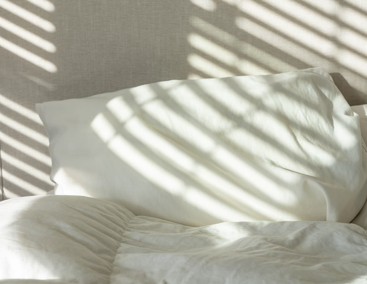 Soft morning light across rumpled white bedding